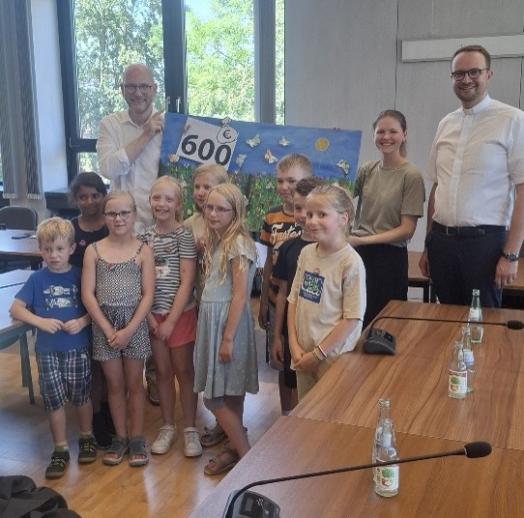 Spendenübergabe der Kommunionkinder aus Roetgen/Rott (vorne), Bürgermeister JormaClauss (3.v.l.), Luisa Kolkenbrock (2.v.r) und Andreas Möhlig (r.) (c) Rebecca Alpmann